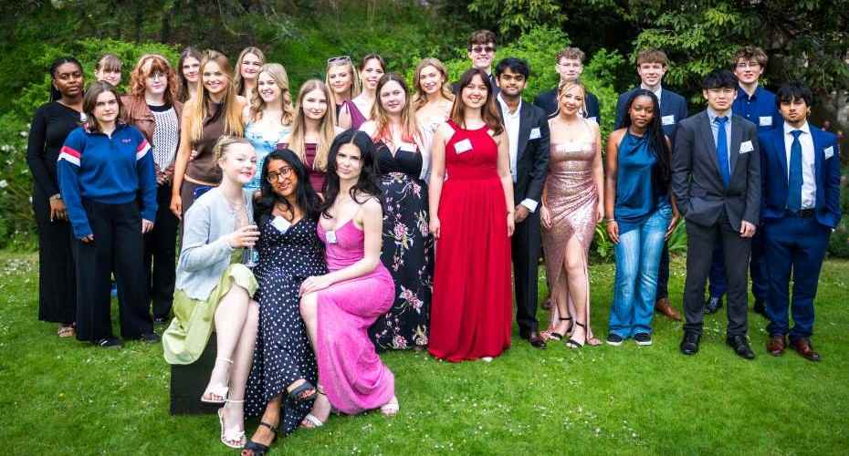 A group of young people attending the Pathways to Law Graduate celebration. They are dressed smartly and on a green lawn with trees behind