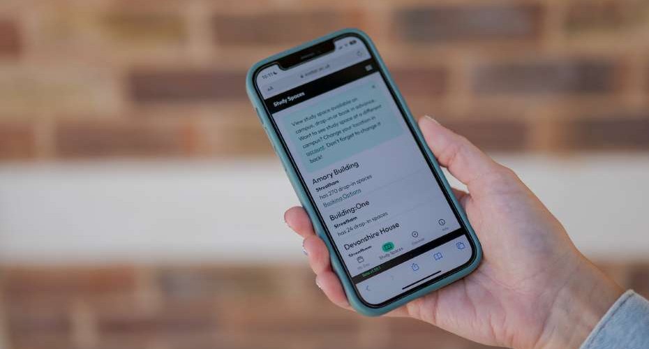 A hand holds a phone displaying the My Exeter app